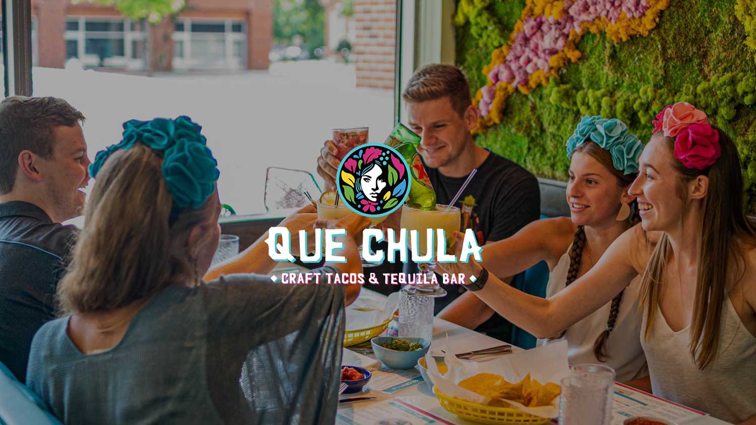 Que Chula Logo Overlay on an image of people cheersing